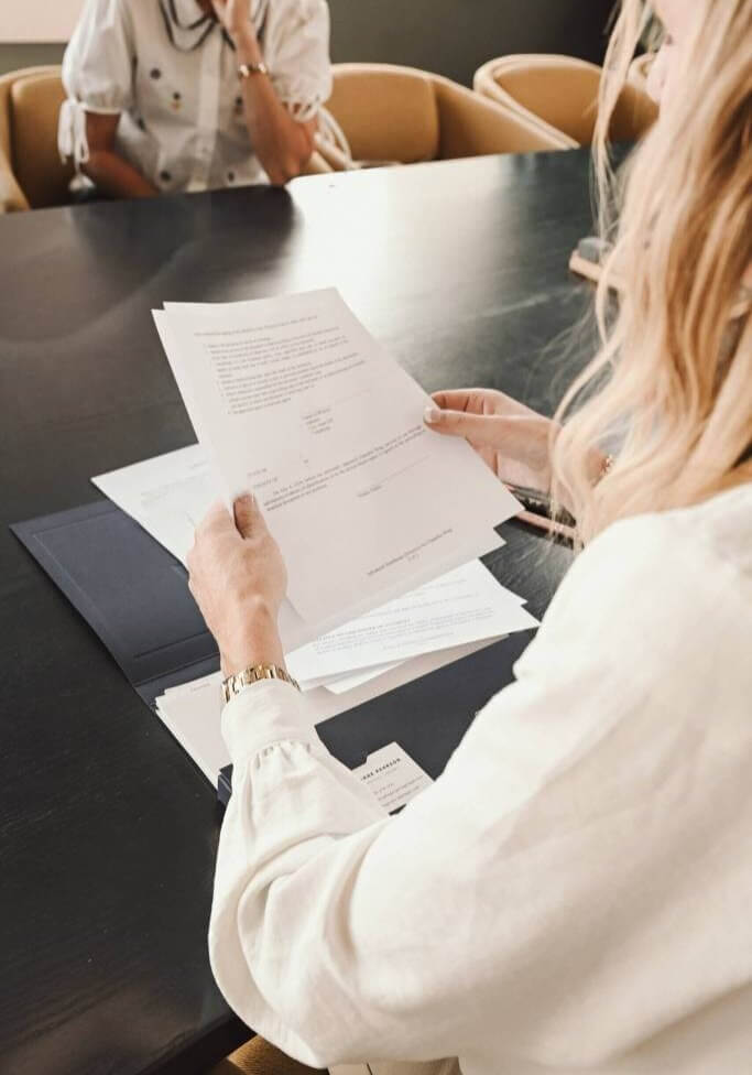 Marne handing over paperwork for clients to review and sign during meeting
